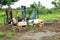 Abandoned damaged forklift trucks with old tire at grassland background