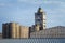 Abandoned damaged old granary against town and blue cloudy sky