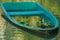 An abandoned, derelict, aqua-blue, fiberglass boat, in a beautiful, reflective garden pond.