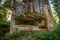 Abandoned, destoyed concrete bunker with embrasure in summer forest