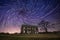 Abandoned farm house with spiral star trails in the sky
