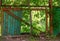 Abandoned fence made of metal and green boards with a broken section