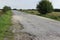 Abandoned field road covered with destroyed asphalt pavement