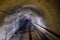 Abandoned flooded underground mine tunnel with pipe and narrow-gauge railway