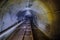 Abandoned flooded underground technical mine tunnel with pipe and narrow-gauge railway