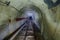 Abandoned flooded underground technical mine tunnel with pipe and narrow-gauge railway