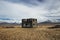 Abandoned forgotten lost place building house farm shed grass landscape in front of mountain range in Vidbord Iceland