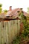 Abandoned house behind old wooden fence, autumn vertical photo