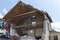 Abandoned house being demolished with mobile walking excavator and rubble and rocks