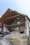 Abandoned house being demolished with mobile walking excavator and rubble and rocks