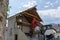 Abandoned house being demolished with mobile walking excavator and rubble and rocks