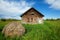 Abandoned house in grassy field with hay bale in front