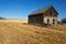 Abandoned house in harvested wheat field