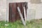 Abandoned house wall with old cracked wooden door garage doors covered with cracked paint and supported with wooden boards