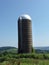 Abandoned landmark vintage barn silo stands solo in NYS field