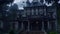 An abandoned mansion surrounded by a dark forest. Bats fly around the mansion and a gargoyle statue stands in front of the