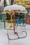 Abandoned non-working children`s carousels in an amusement park strewn with snow on a bright sunny winter frosty day