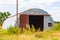 An abandoned old corrugated metal clad barn surrounded by wild grass