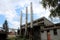 Abandoned old industrial complex building with destroyed backyard wall next to three tall metal chimneys