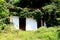 Abandoned old outdoor beach changing room with missing doors and broken roof surrounded with overgrown trees