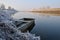 Abandoned old row boat moored by the river bank in winter. Calm river, frost