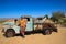Abandoned old rusty cars in the desert of Namibia and a plump white tourist girl near the Namib-Naukluft National Park