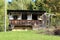 Abandoned old vintage dilapidated destroyed concrete and wooden suburban family house with front porch on top of small hill