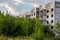 Abandoned and overgrown five-story house in ghost-town, summer