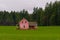 An abandoned pink color farmhouse in a green field on cloudy autumn day