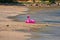 Abandoned pink flamingo swim ring on sand beach