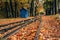 Abandoned railway station in the autumn forest or old public park with yellow leaves fallen - beautiful autumn