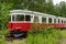 Abandoned red and white rail bus standing on an overgrown track