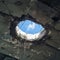 Abandoned rooftop damaged ceiling reveals cloudy sky through hole