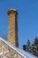 Abandoned ruin of oven chimney. Broken furnace. Snowy roof, stork slot and blue sky background in the winter.