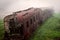 Abandoned rusting train and empty train tracks photographed in a foggy day