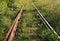 Abandoned rusty and active railway track overgrown with grass