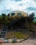Abandoned rusty UFO house with concrete stairs under the cloudy sky in Wanli UFO Village, Taiwan