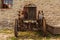 Abandoned rusty wheeled tractor against the background of a gray stone wall. Front view