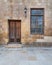 Abandoned stone bricks wall with wooden door, wrought iron window and antique lantern