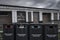 An abandoned toilet block, decaying with age, with four recycling bins in the foreground, also in poor condition,