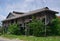 An abandoned traditional style private wooden building with weed grass growing in Southeast Asia