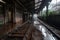 an abandoned train station, with rusting metal and rainwater puddles on the platform