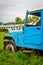 Abandoned vintage car blue lush green grass in college campus