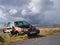 An abandoned, white, 1993 VW Golf now coloured with rust decays in a rural setting.