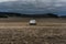 Abandoned white car on a yellow corn field with dark clouds and