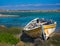 abandoned wooden fish boat at the shore. The boat is destroyed and rusty an completely useless with the sea and the blue sky at