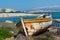 abandoned wooden fish boat at the shore. The boat is destroyed and rusty an completely useless with the sea and the blue sky at