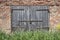 An abandoned wooden gate in a brick wall is padlocked