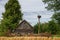 Abandoned wooden house in russian village and stork in nest on pillar. Rural landscape