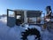 Abandoned, wrecked tractor buried in snow under the blue sky in the winter